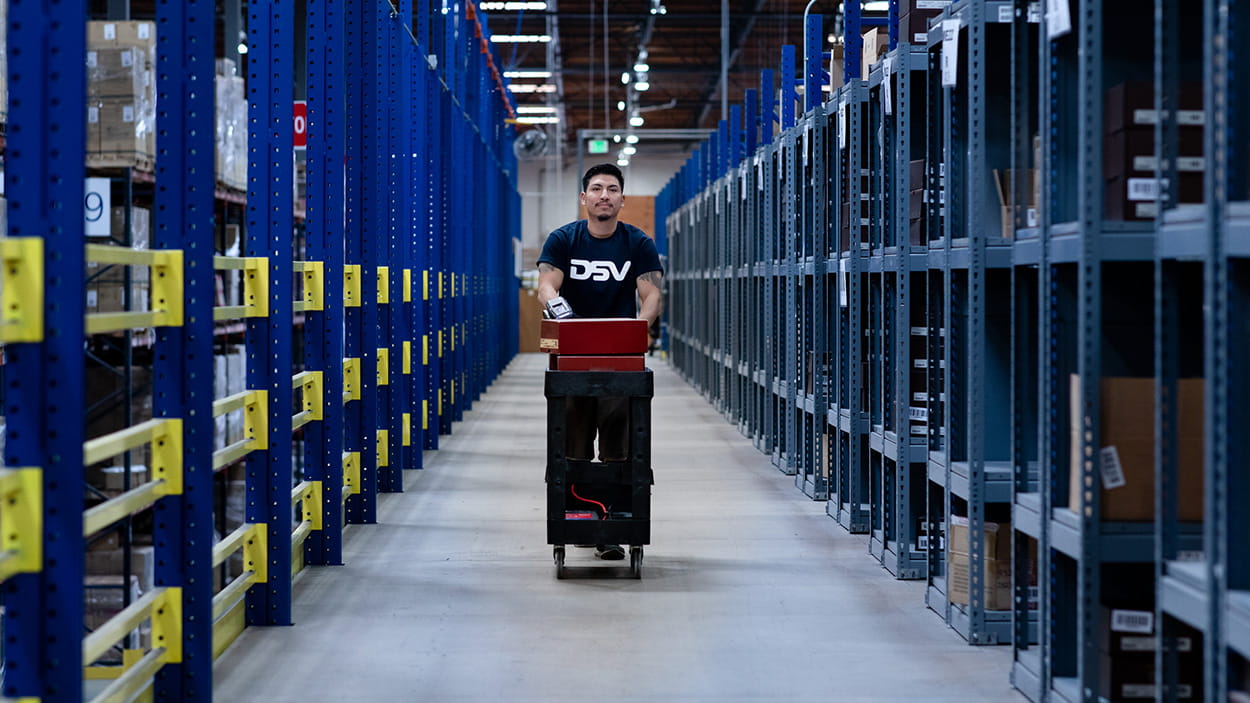 DSV medarbeider triller tralle mellom lagerreoler.